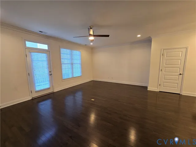 an empty room with wooden floor chandelier fan and windows