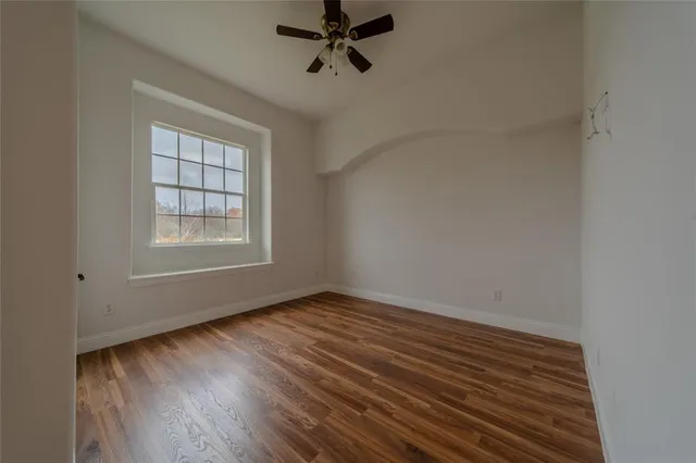 an empty room with wooden floor cabinet and windows