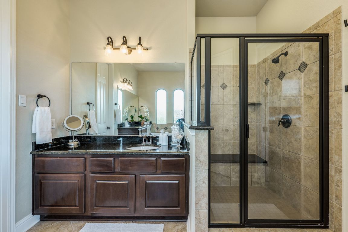 306 Tavish Trail Austin, TX 78738 - Photo 29 of 40 a bathroom with a granite countertop sink a mirror and shower