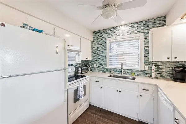a kitchen with a sink a refrigerator a window and cabinets