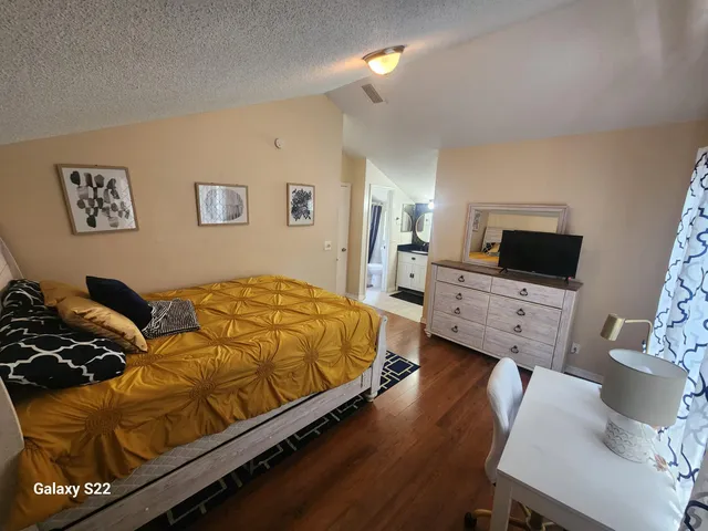 a bedroom with a bed a couch and a flat screen tv