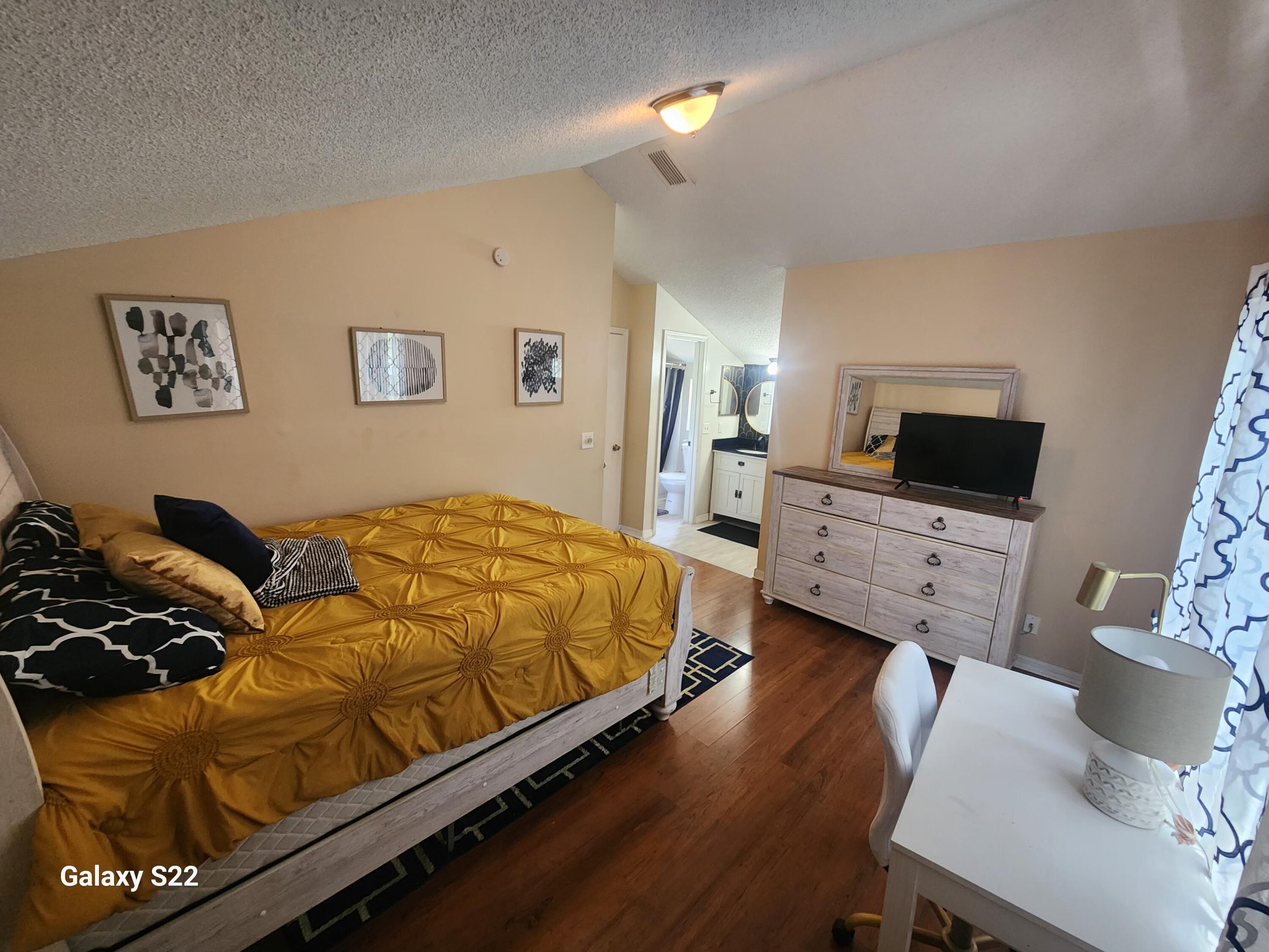 5884 Dewberry Way West Palm Beach, FL 33415 - Photo 20 of 26 a bedroom with a bed a couch and a flat screen tv