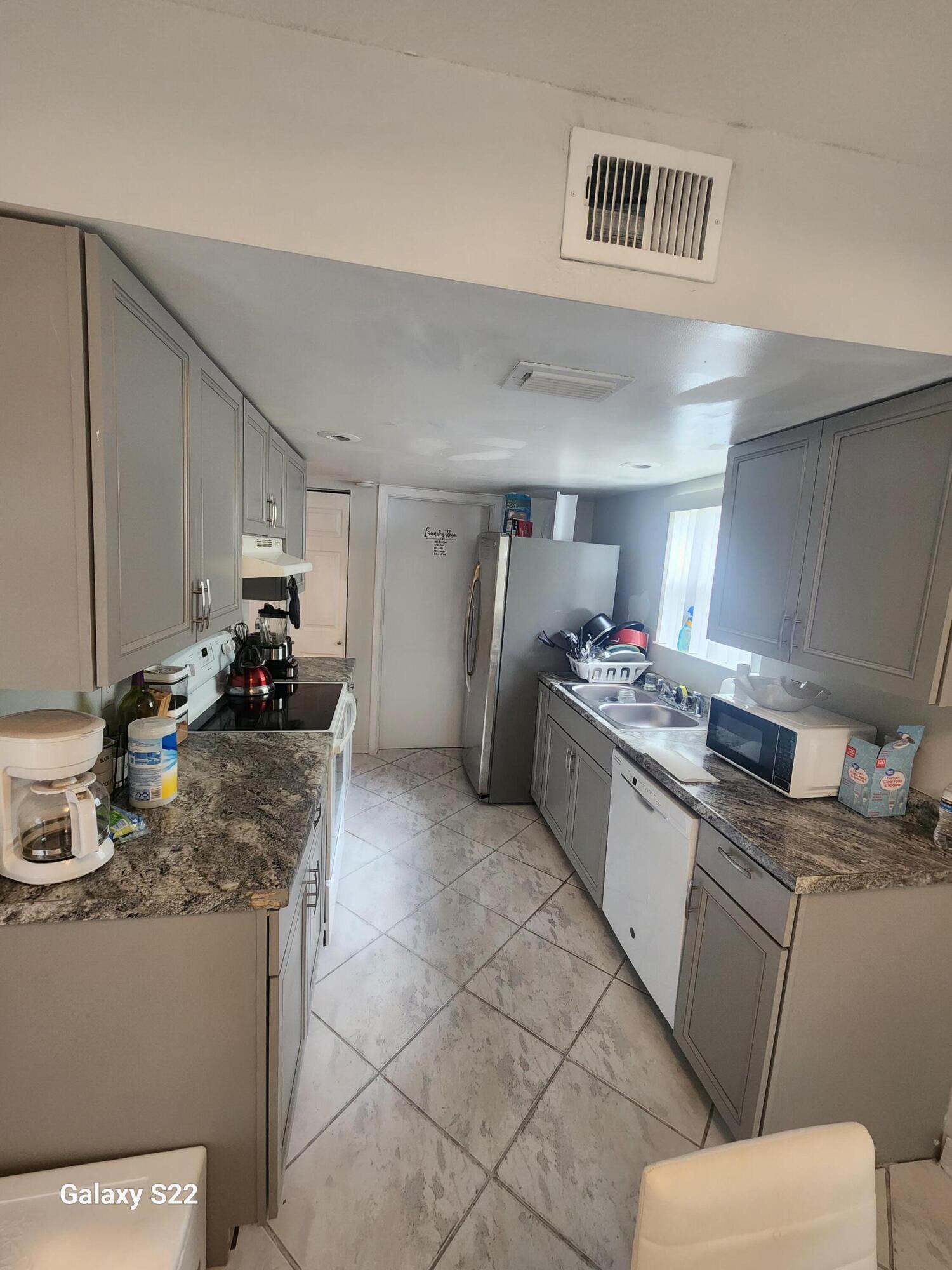 5884 Dewberry Way West Palm Beach, FL 33415 - Photo 6 of 26 a kitchen with granite countertop a sink stove and cabinets