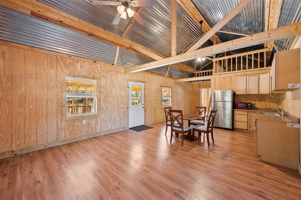134 Maple Avenue Streetman, TX 75859 - Photo 12 of 19 Dining room featuring high vaulted ceiling, light wood-style flooring, wooden walls, ceiling fan, and beam ceiling