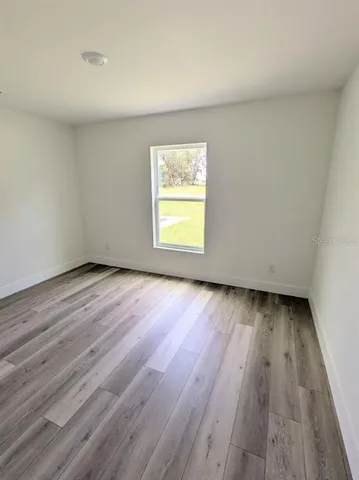 a view of an empty room and wooden floor and window