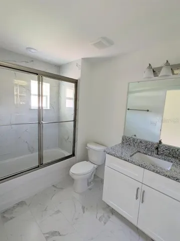 a bathroom with a granite countertop sink a toilet and a shower
