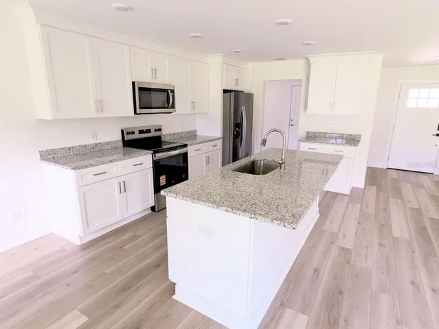 a kitchen with a sink wooden floor and stainless steel appliances