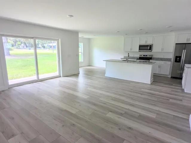 a view of an empty room with kitchen and a window