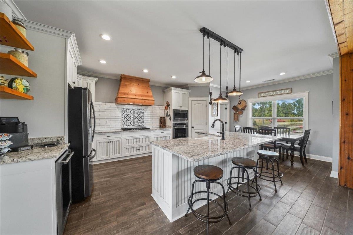 4374 Gainsville Road Mason, TN 38049 - Photo 12 of 40 Kitchen with decorative backsplash, light stone counters, hanging light fixtures, open shelves, and a kitchen bar