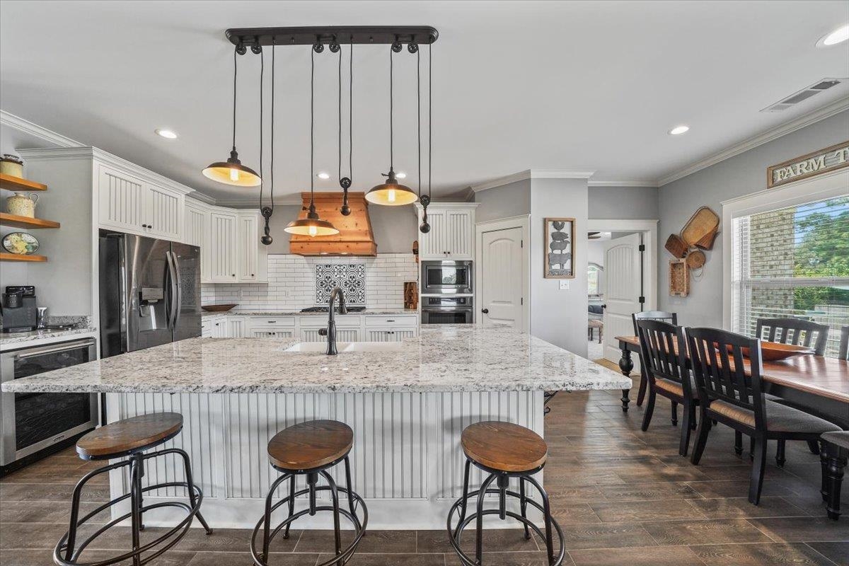 4374 Gainsville Road Mason, TN 38049 - Photo 13 of 40 Kitchen with light stone counters, white cabinets, a large island with sink, pendant lighting, and a breakfast bar
