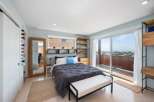a living room with a balcony a bed and glass walk in closet