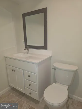 a bathroom with a toilet sink vanity and mirror