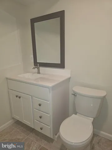 a bathroom with a toilet sink vanity and mirror