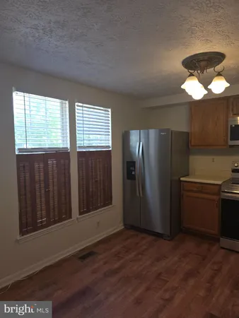 a view of a kitchen with a stove wooden cabinets and a refrigerator