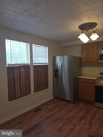 a view of a kitchen with a stove wooden cabinets and a refrigerator