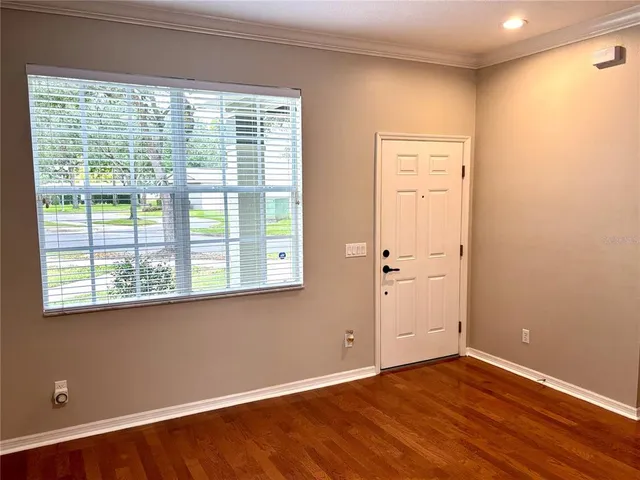 a view of an empty room with wooden floor and a window