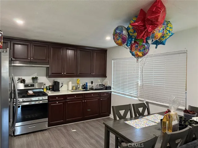 a kitchen with granite countertop a stove a sink dishwasher and cabinets with wooden floor