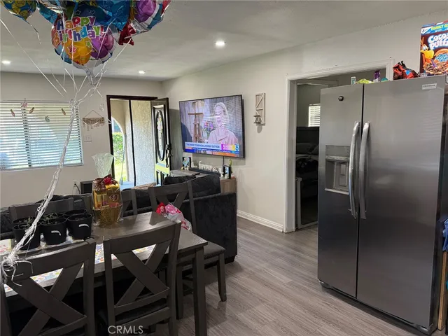 a kitchen with stainless steel appliances granite countertop a refrigerator a sink dishwasher a dining table and chairs with wooden floor