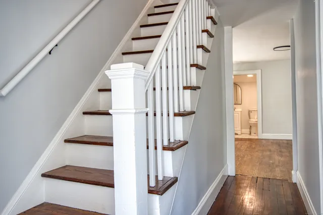 a view of staircase with wooden floor and white walls