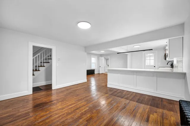 a view of empty room with wooden floor and kitchen