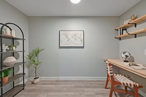 a view of a workspace room with wooden floor and a potted plant
