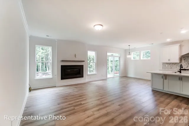 a view of a kitchen and an empty room with wooden floor and a fireplace