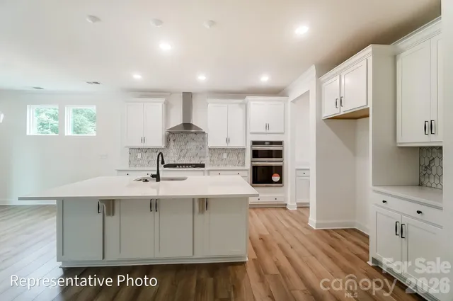 a kitchen with stainless steel appliances a sink cabinets and wooden floor