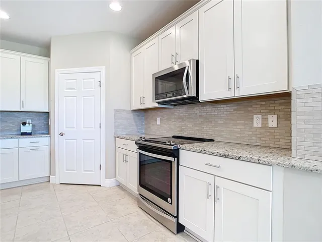 a kitchen with granite countertop white cabinets and stainless steel appliances