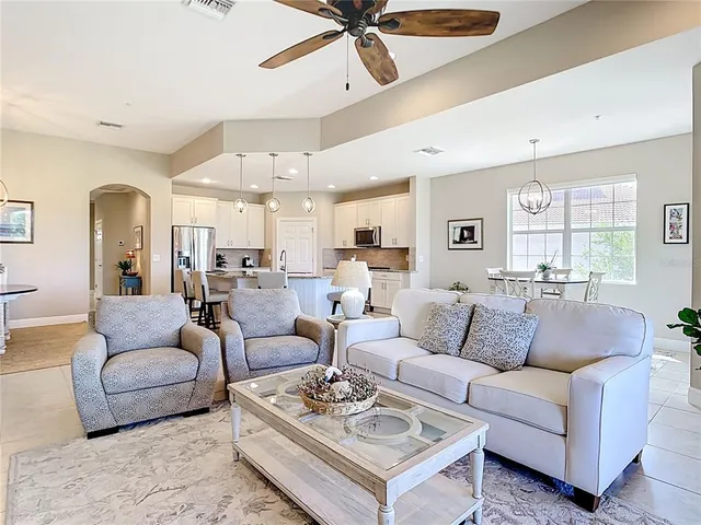 a living room with furniture kitchen view and a chandelier