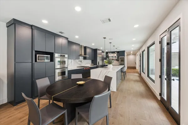 a dining room with stainless steel appliances kitchen island granite countertop a dining table chairs refrigerator and cabinets