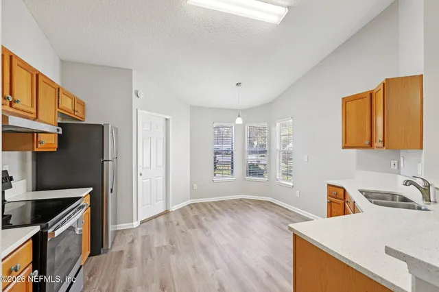 a kitchen with granite countertop a stove a sink and a refrigerator
