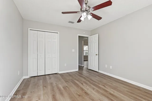 an empty room with wooden floor fan and windows