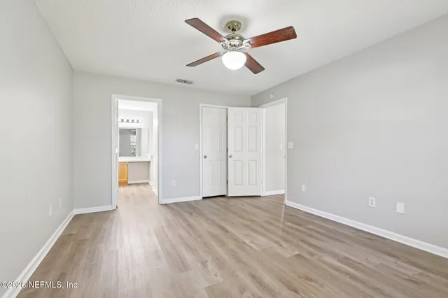 an empty room with wooden floor ceiling fan and windows