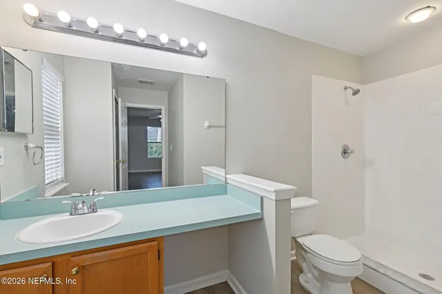 a bathroom with a granite countertop sink toilet and a mirror