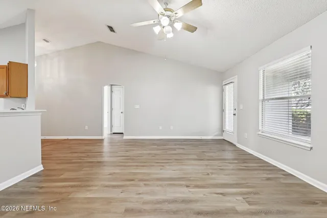 a view of an empty room with window and wooden floor