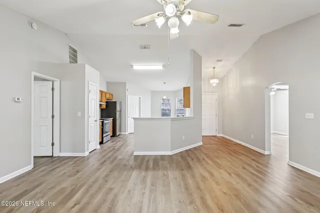 a view of kitchen and empty room with wooden floor