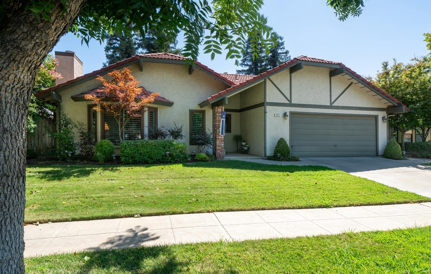 1021 Pistachio Avenue Clovis, CA 93611 - Photo 25 of 27 a view of a white house with a small yard plants and a large tree