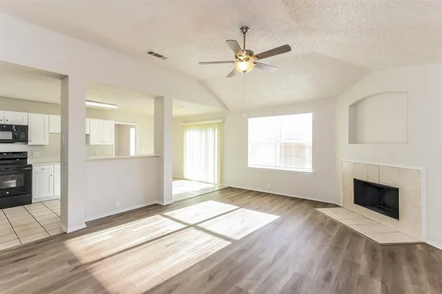 a view of an empty room with window and wooden floor