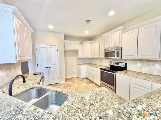 a kitchen with kitchen island granite countertop a sink stainless steel appliances and cabinets