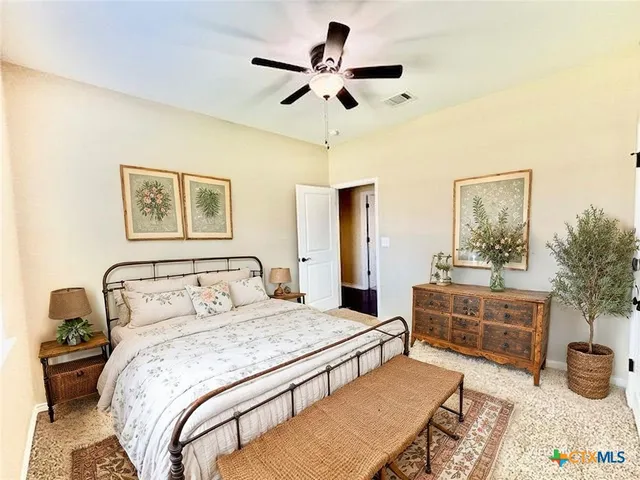 a bedroom with a bed a dresser and potted plants