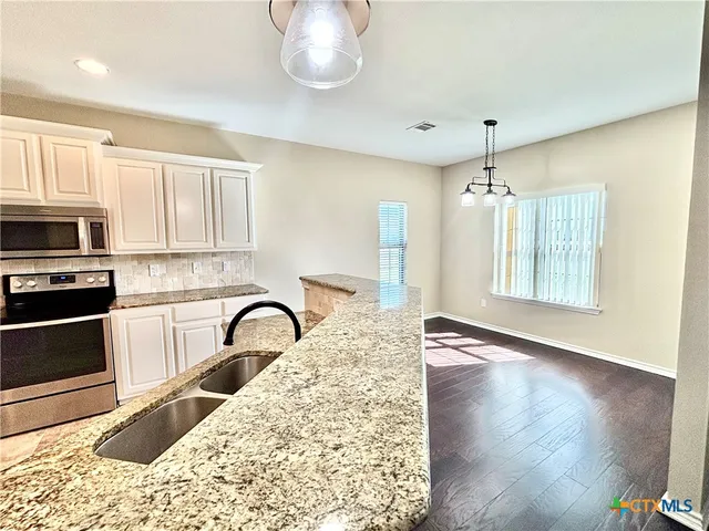 a kitchen with stainless steel appliances granite countertop a stove a sink and a refrigerator
