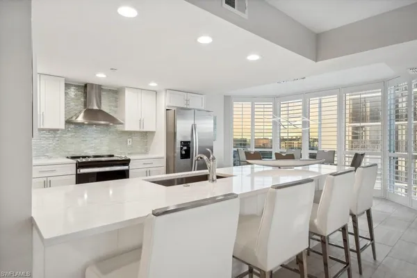 a kitchen with stainless steel appliances granite countertop a stove a sink a refrigerator and white cabinets with wooden floor