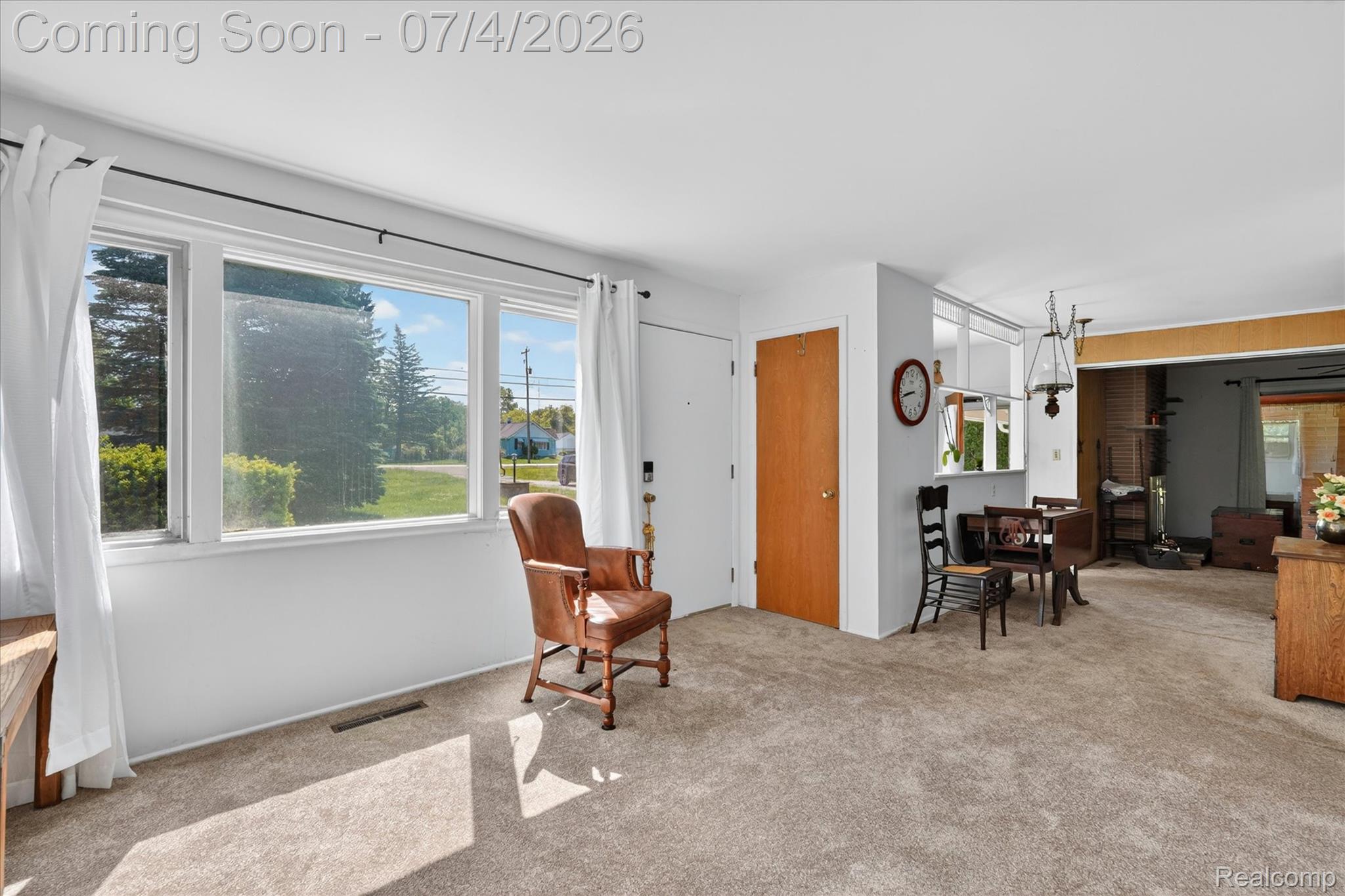 2091 North Irish Road Davison, MI 48423 - Photo 4 of 25 Spacious living area featuring light-toned carpeting, ample natural light from multiple windows, and a warm wood-finish interior door