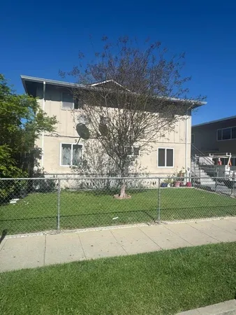 a view of a house with a yard and a large tree