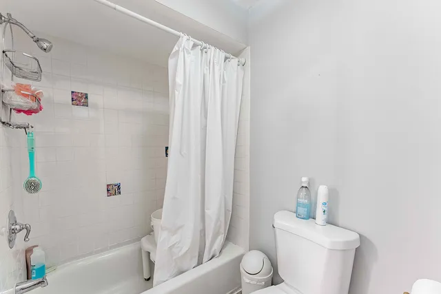 a white toilet sitting next to a bath tub