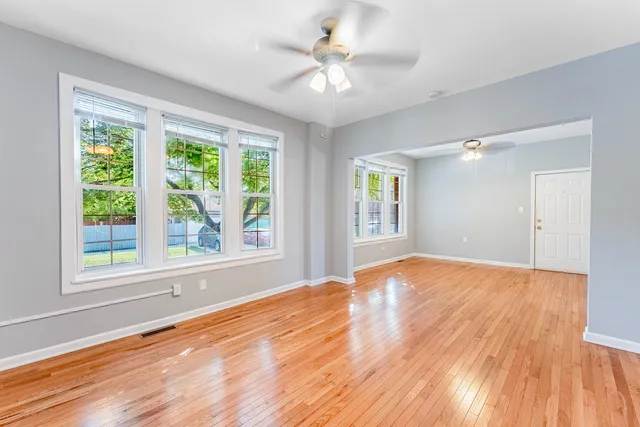a view of an empty room with a window and wooden floor