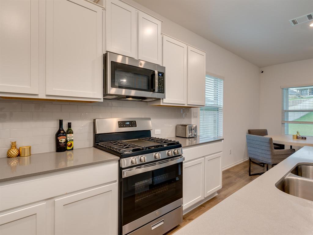 1208 Sweetspire Street Leander, TX 78641 - Photo 8 of 36 Modern kitchen featuring white shaker cabinetry, stainless steel appliances, a subway tile backsplash, and light-toned countertops