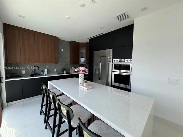 a kitchen with stainless steel appliances a sink a stove a refrigerator and cabinets