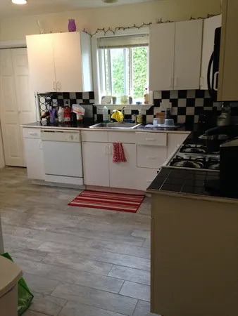 a kitchen with a sink appliances cabinets and a window
