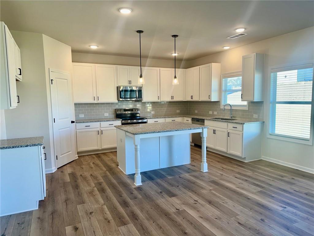 325 Rodeo Drive Auburn, GA 30011 - Photo 16 of 39 a kitchen with stainless steel appliances kitchen island granite countertop wooden floors wooden cabinets and window